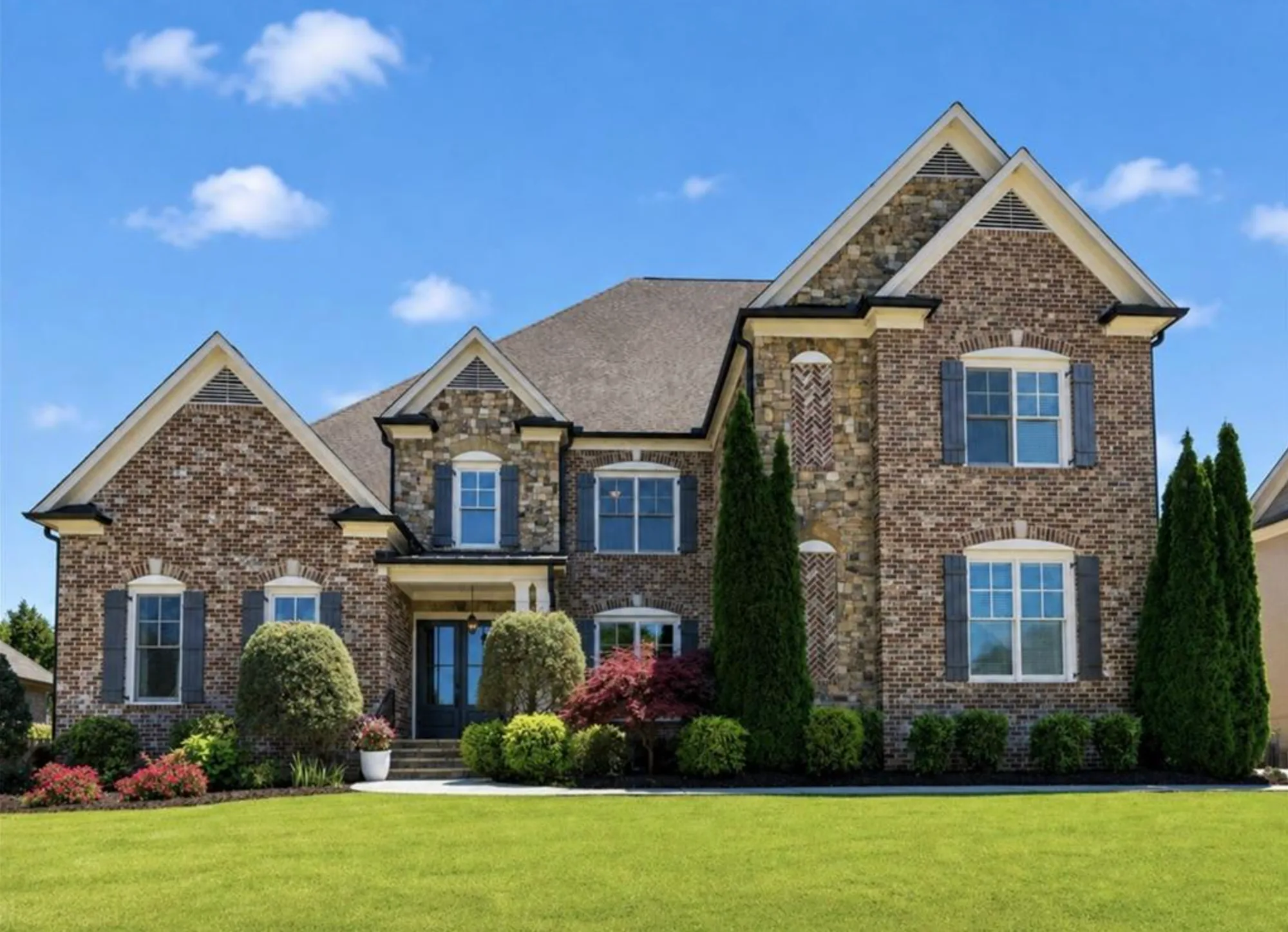 Brick and stone traditional home with gabled rooflines and manicured front lawn — 12711 Ruths Farm Way, Alpharetta