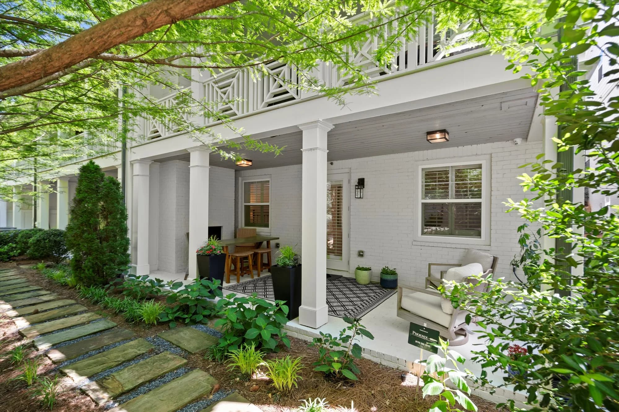 Front of 420 Banbury Crossing facing the Alpha Loop — a white townhome with a covered front porch and stone walkway framed by mature landscaping.