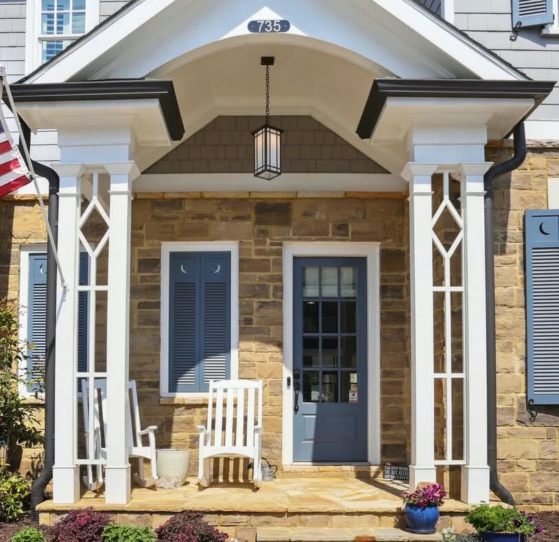 Covered Craftsman front porch with columns and a rocking-chair seating area.