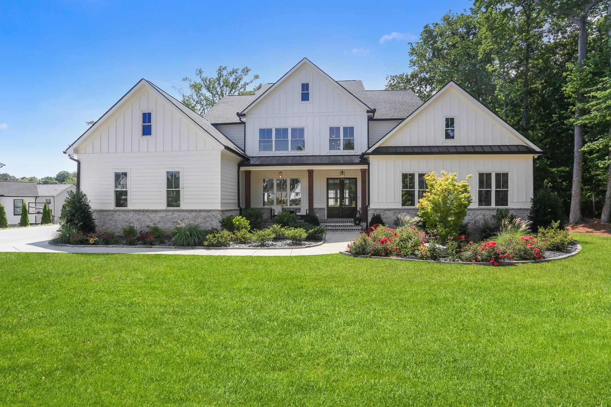 Twilight view of the white modern-farmhouse front exterior with warm interior lighting and a landscaped front lawn