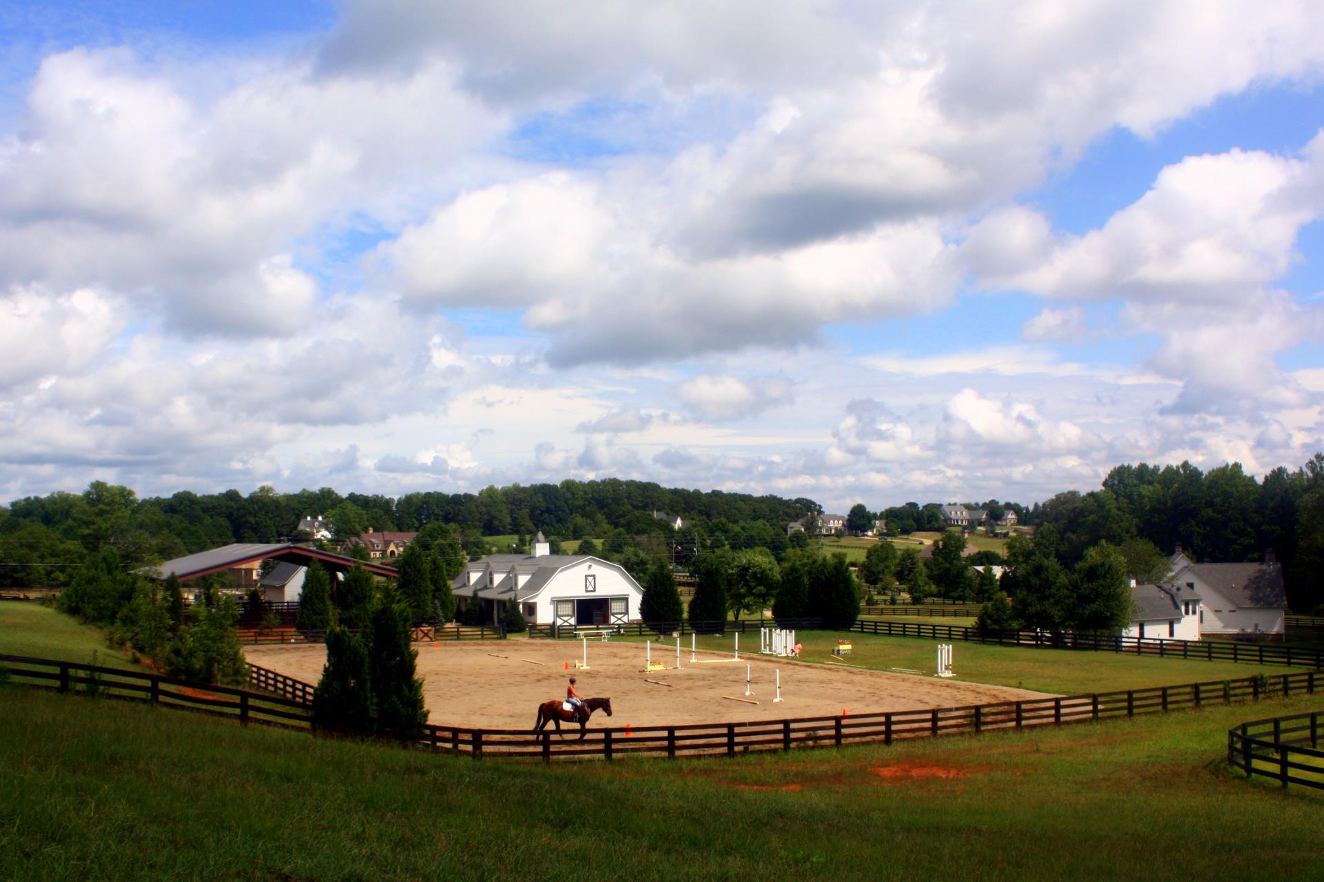 Equestrian estate with a riding arena, white barn, and rolling pasture in Milton, Georgia